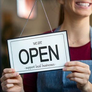 Woman turning over Open sign in shop window
