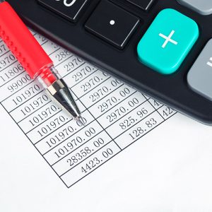 Pen and calculator on top of paper with table of numbers