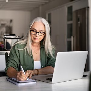 Woman using laptop and pad with pen