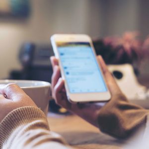Person using phone while drinking from a mug